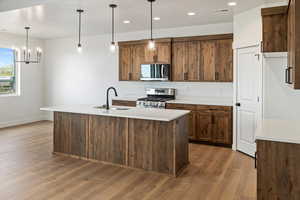 Kitchen with baseboards, appliances with stainless steel finishes, a sink, and light wood-style flooring