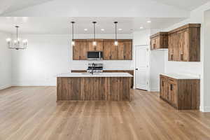 Kitchen featuring a sink, light wood-style flooring, stainless steel microwave, baseboards, and stove