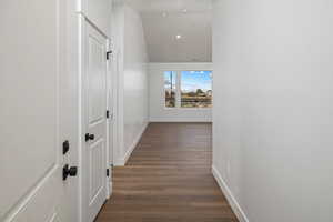 Hallway with recessed lighting, dark wood finished floors, lofted ceiling, and baseboards