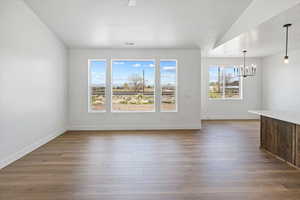 Interior space with baseboards, wood finished floors, visible vents, and a chandelier