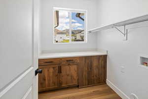 Clothes washing area featuring light wood-style flooring, baseboards, cabinet space, and hookup for a washing machine