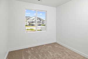 Carpeted empty room with a residential view, baseboards, and visible vents