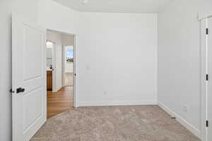 Unfurnished bedroom with light colored carpet and baseboards