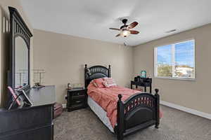 Bedroom featuring dark colored carpet, visible vents, baseboards, and ceiling fan