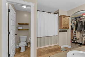 Bathroom featuring tile patterned floors, a shower with curtain, a spacious closet, and toilet