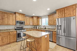 Kitchen with a sink, light tile patterned flooring, a breakfast bar area, stainless steel appliances, and backsplash