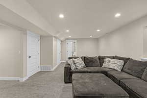 Living area with light colored carpet, baseboards, visible vents, and recessed lighting