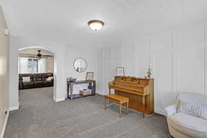 Living area with arched walkways, carpet floors, and baseboards