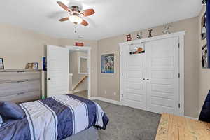 Carpeted bedroom with a ceiling fan, baseboards, and a closet