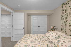 Carpeted bedroom featuring a textured ceiling and a closet