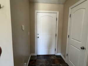 Doorway to outside featuring baseboards and stone finish flooring