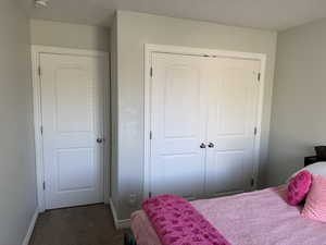 Bedroom with dark carpet, baseboards, and a closet