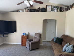 Carpeted living room with ceiling fan, lofted ceiling, a textured ceiling, and baseboards