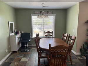 Dining area with stone tile floors, baseboards, an inviting chandelier, and visible vents