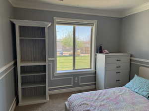 Carpeted bedroom with ornamental molding