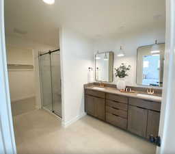 Ensuite bathroom featuring ensuite bath, a marble finish shower, a sink, and double vanity