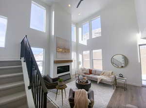 Living area with wood finished floors, a healthy amount of sunlight, a towering ceiling, and stairs