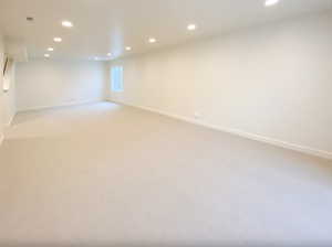 Basement featuring light colored carpet, baseboards, and recessed lighting