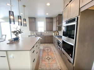 Kitchen featuring a sink, decorative backsplash, light wood-type flooring, stainless steel appliances, and light countertops