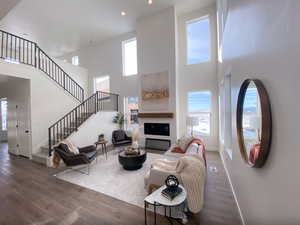 Living room featuring baseboards, recessed lighting, wood finished floors, a high ceiling, and stairway