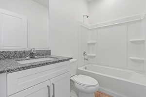 Full bathroom featuring wood finished floors, toilet, vanity, and  shower combination