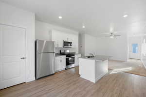 Kitchen with white cabinets, appliances with stainless steel finishes, a sink, and ceiling fan