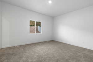 Carpeted spare room with visible vents and baseboards