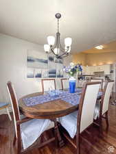 Dining room featuring an inviting chandelier, dark wood-style flooring, a textured ceiling, and baseboards