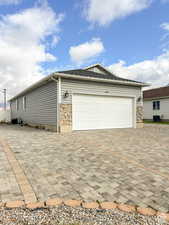 Exterior space featuring stone siding, central AC unit, and decorative driveway