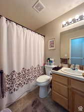 Full bath featuring tile patterned floors, a textured ceiling, toilet, visible vents, and vanity