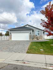 Ranch-style house with an attached garage, fence, stone siding, and a front yard