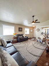 Living area featuring a textured ceiling, wainscoting, a ceiling fan, wood finished floors, and a decorative wall