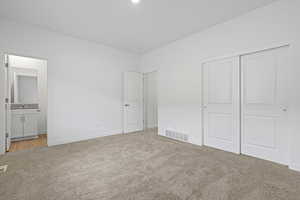 Unfurnished bedroom with a closet, baseboards, visible vents, and light colored carpet