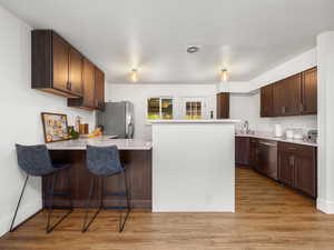 Kitchen with stainless steel appliances, a peninsula, visible vents, light countertops, and a breakfast bar area