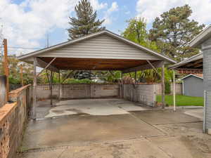 View of car parking featuring fence, driveway, and a detached carport