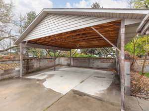 View of vehicle parking with a detached carport and fence