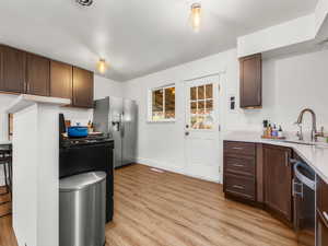 Kitchen featuring light countertops, light wood-style floors, appliances with stainless steel finishes, and a sink