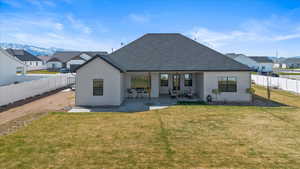 Rear view of property featuring a lawn, a patio area, a fenced backyard, and roof with shingles