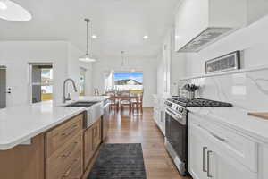 Kitchen with light wood-style flooring, a sink, recessed lighting, decorative light fixtures, and appliances with stainless steel finishes