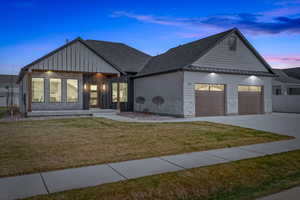 View of front of house featuring a standing seam roof, concrete driveway, an attached garage, board and batten siding, and a front yard