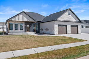 Modern inspired farmhouse with board and batten siding, a garage, a front yard, and concrete driveway