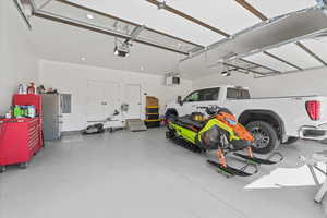 Garage with recessed lighting, freestanding refrigerator, and a garage door opener