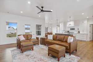 Living room featuring ceiling fan, baseboards, light wood-style flooring, and recessed lighting