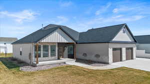 Back of house featuring driveway, a yard, board and batten siding, and a garage