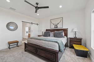 Owner's Suite Bedroom with visible vents, recessed lighting, light colored carpet, and a barn door