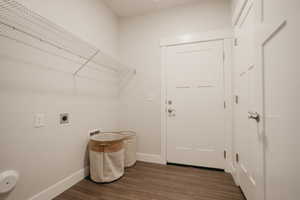 Clothes washing area with dark wood-style floors, baseboards, electric dryer hookup, and laundry area