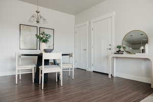 Dining space featuring an inviting chandelier, dark wood-type flooring, and baseboards