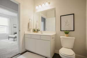 Bathroom featuring wood finished floors, baseboards, vanity, and toilet