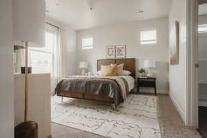 Bedroom with light carpet, visible vents, and multiple windows