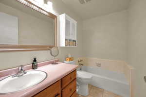 Bathroom featuring a garden tub, tile patterned flooring, vanity, and toilet